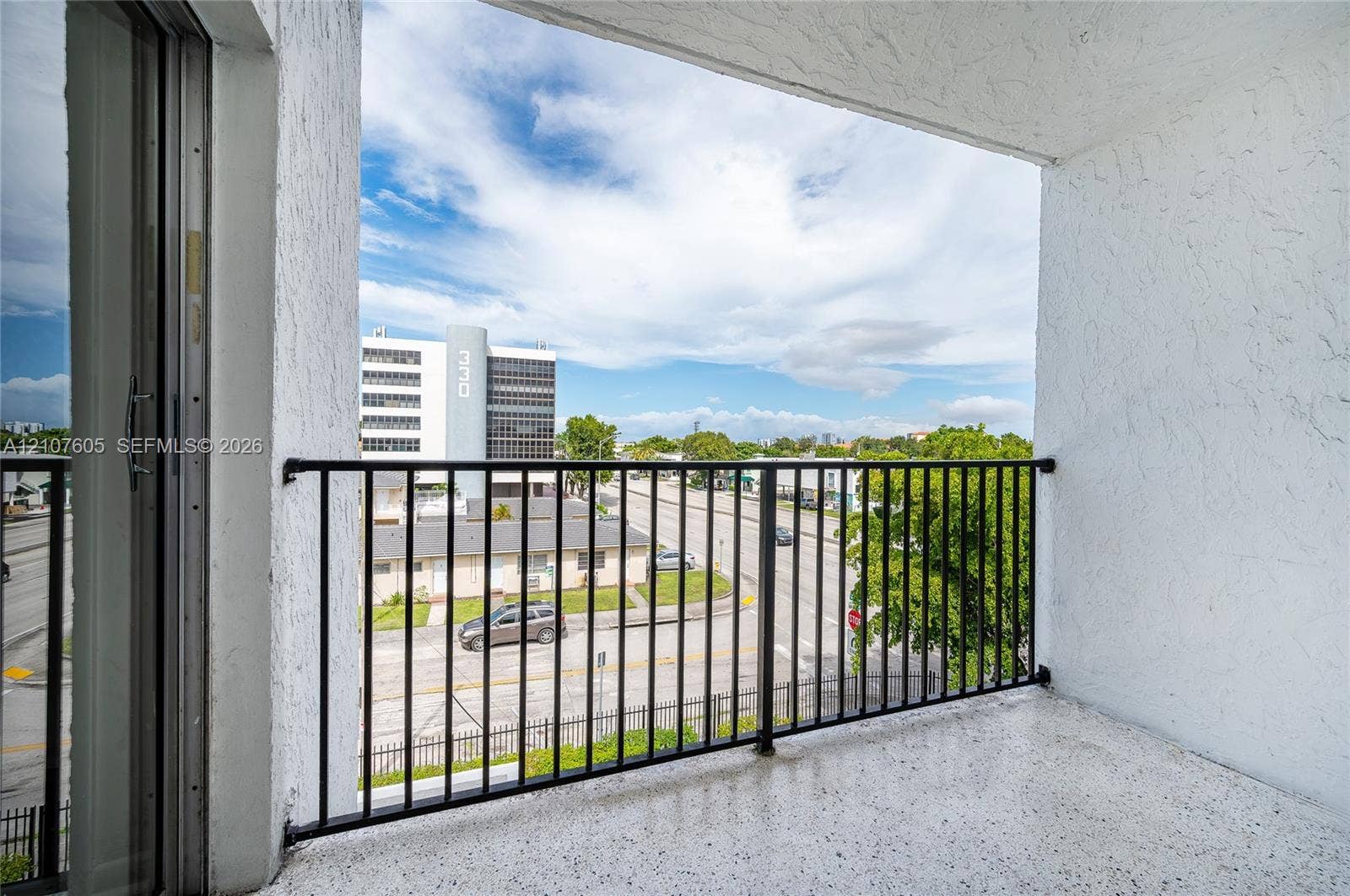 444 SW 27th Avenue, #42, Miami, Miami, FL 33135 Covered balcony featuring textured concrete walls, speckled flooring, and a black metal railing