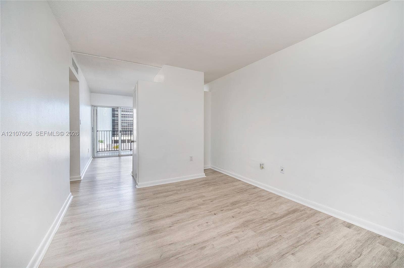 444 SW 27th Avenue, #42, Miami, Miami, FL 33135 Neutral interior space featuring wood-finish flooring, smooth white walls, and sliding glass doors with access to a railed balcony