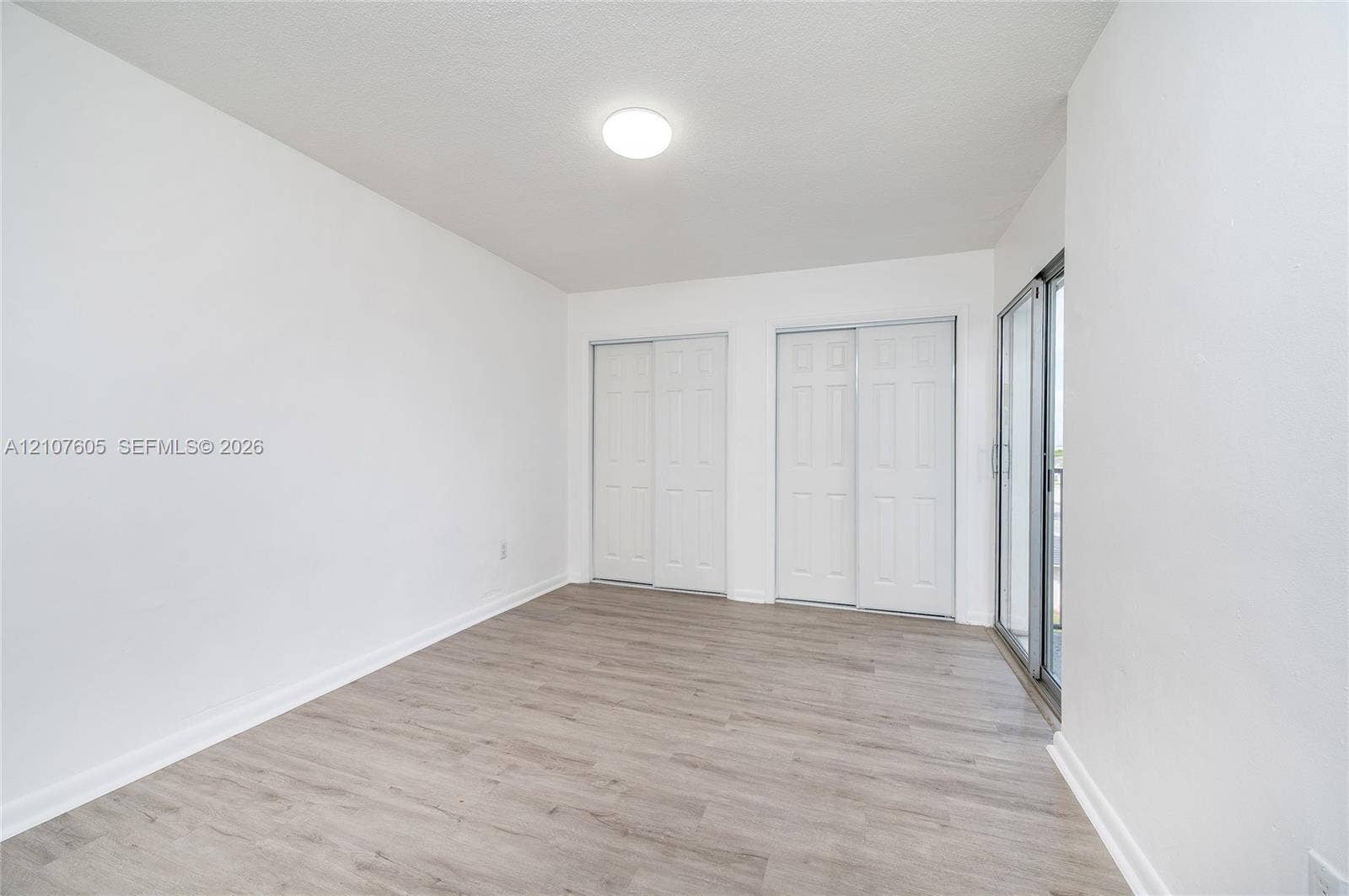 444 SW 27th Avenue, #42, Miami, Miami, FL 33135 Room featuring wood-finish flooring, two sets of white double-door closets, and a glass sliding door