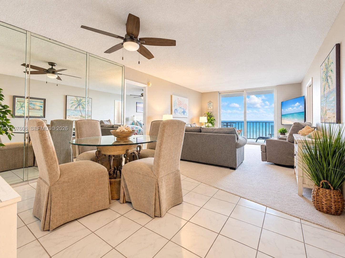 2000 S Ocean Boulevard, #12F, Lauderdale-By-The-Sea, Lauderdale By The Sea, FL 33062 Open-concept living space featuring ceramic tile flooring, full-wall mirrored closet, ceiling fan with integrated lighting, and floor-to-ceiling sliding glass doors opening to an ocean backdrop