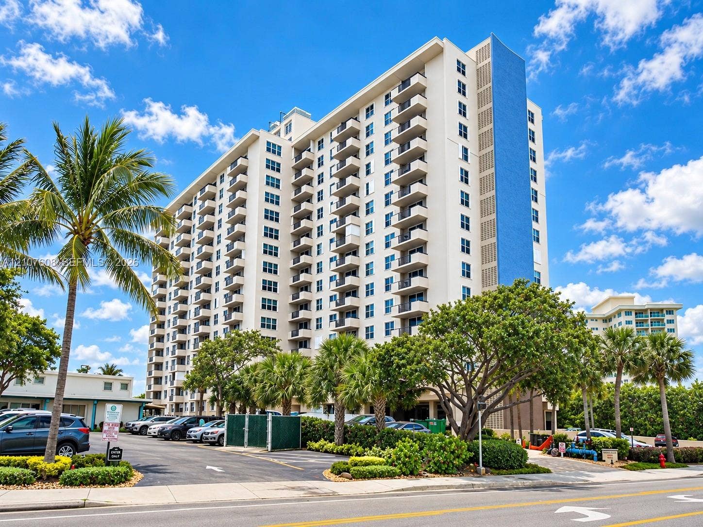 2000 S Ocean Boulevard, #12F, Lauderdale-By-The-Sea, Lauderdale By The Sea, FL 33062 High-rise residential exterior featuring stacked private balconies, a distinctive vertical blue facade accent, and paved surface parking framed by mature palm trees and established landscaping