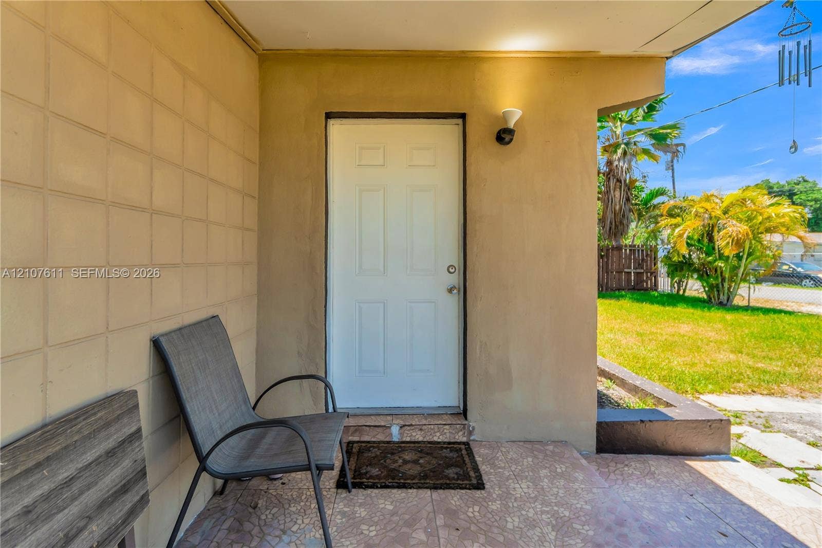 2910 NW 47th Street, Miami, FL 33142 Covered entryway featuring textured concrete block wall, decorative tiled flooring, and exterior wall-mounted light fixture