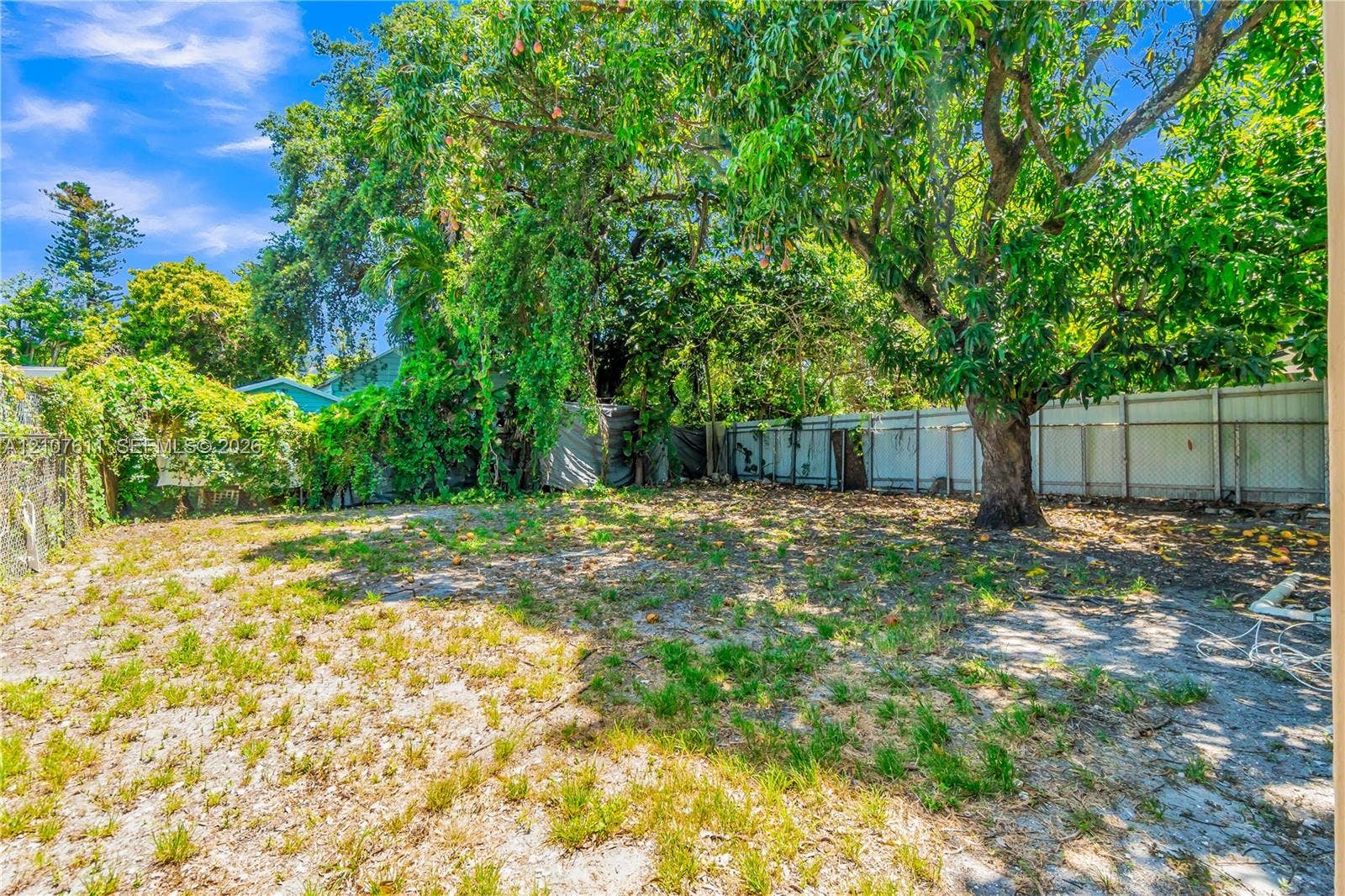 2910 NW 47th Street, Miami, FL 33142 Expansive backyard featuring mature trees, partial perimeter fencing, and open ground