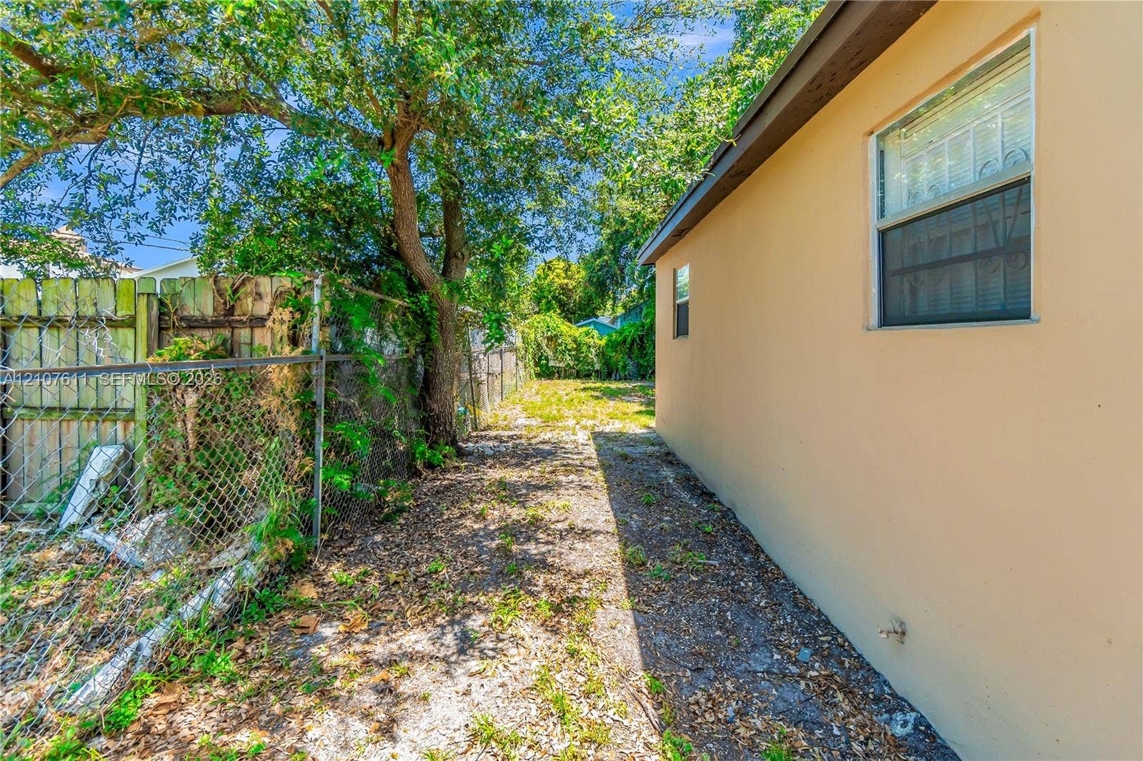 2910 NW 47th Street, Miami, FL 33142 Exterior side yard featuring stucco siding, single-hung windows, and chain-link perimeter fencing