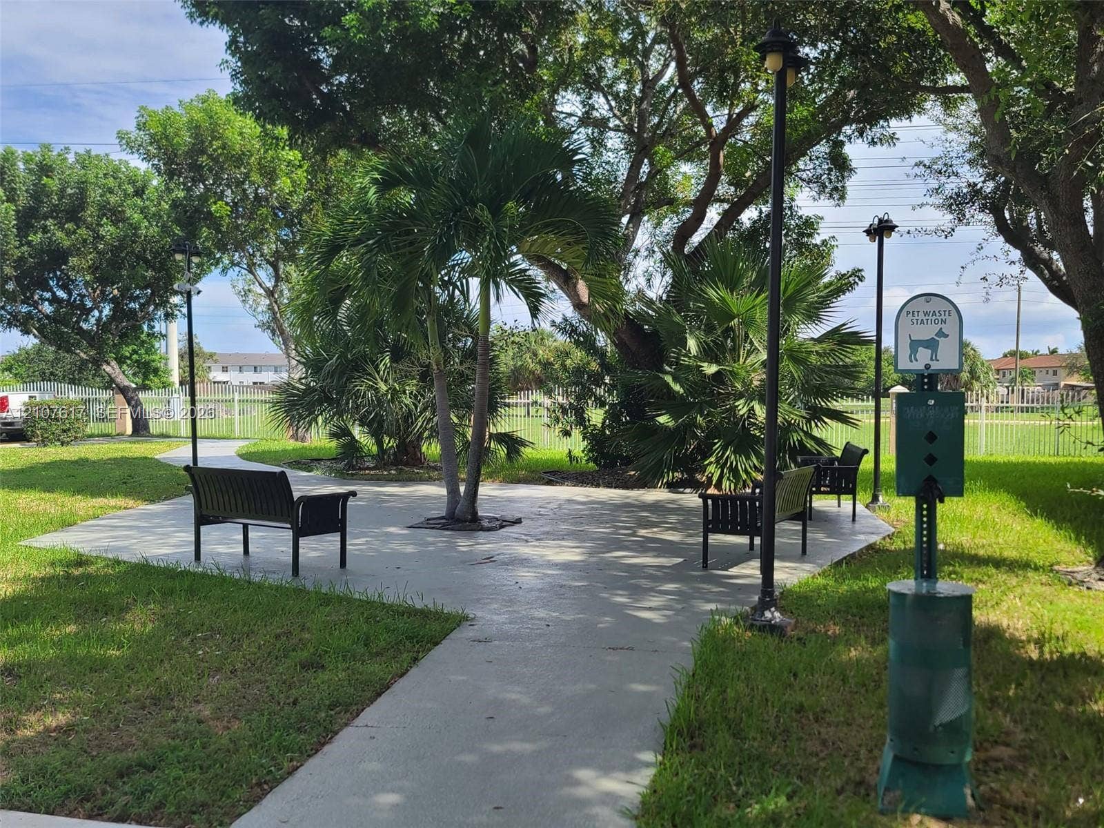 17415 NW 75th Place, #103, Hialeah, Hialeah, FL 33015 Landscaped common area featuring paved pathways, metal benches, mature palm trees, and integrated lighting fixtures