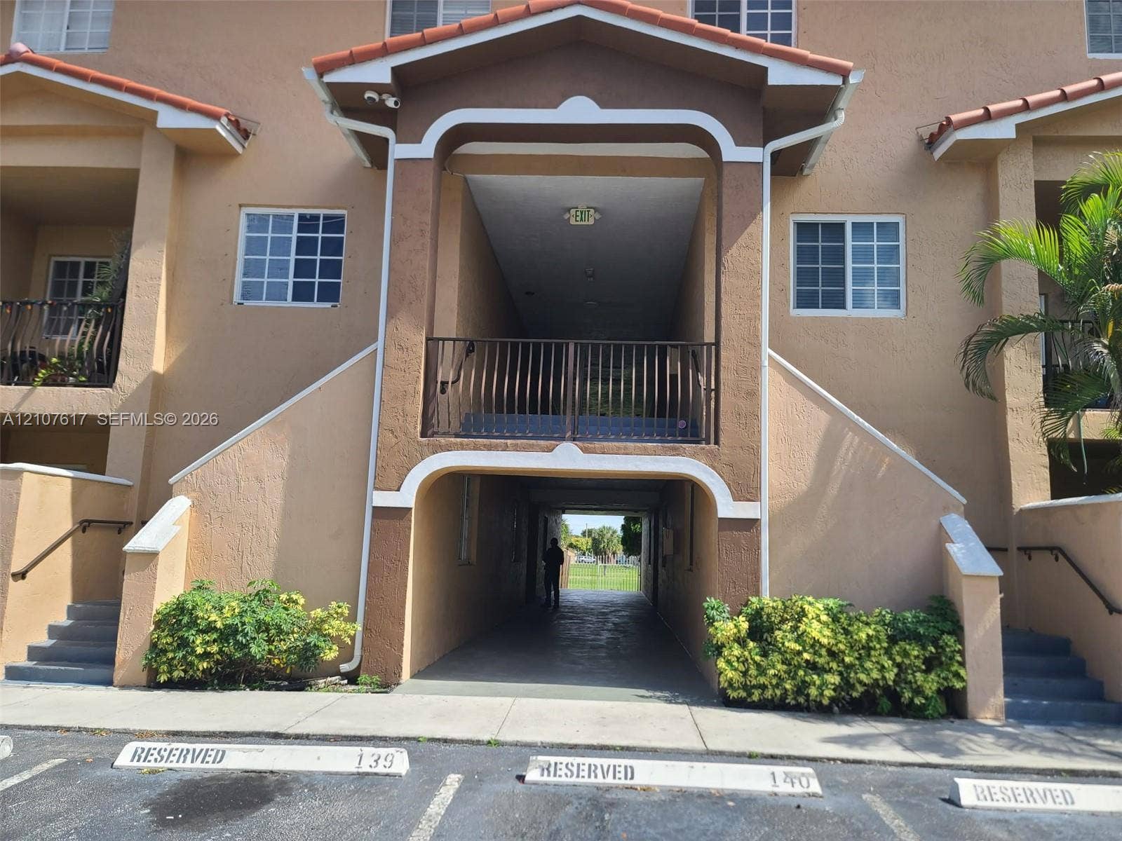 17415 NW 75th Place, #103, Hialeah, Hialeah, FL 33015 Stucco exterior with an arched entryway, elevated balcony featuring metal railings, and two sets of concrete exterior stairs