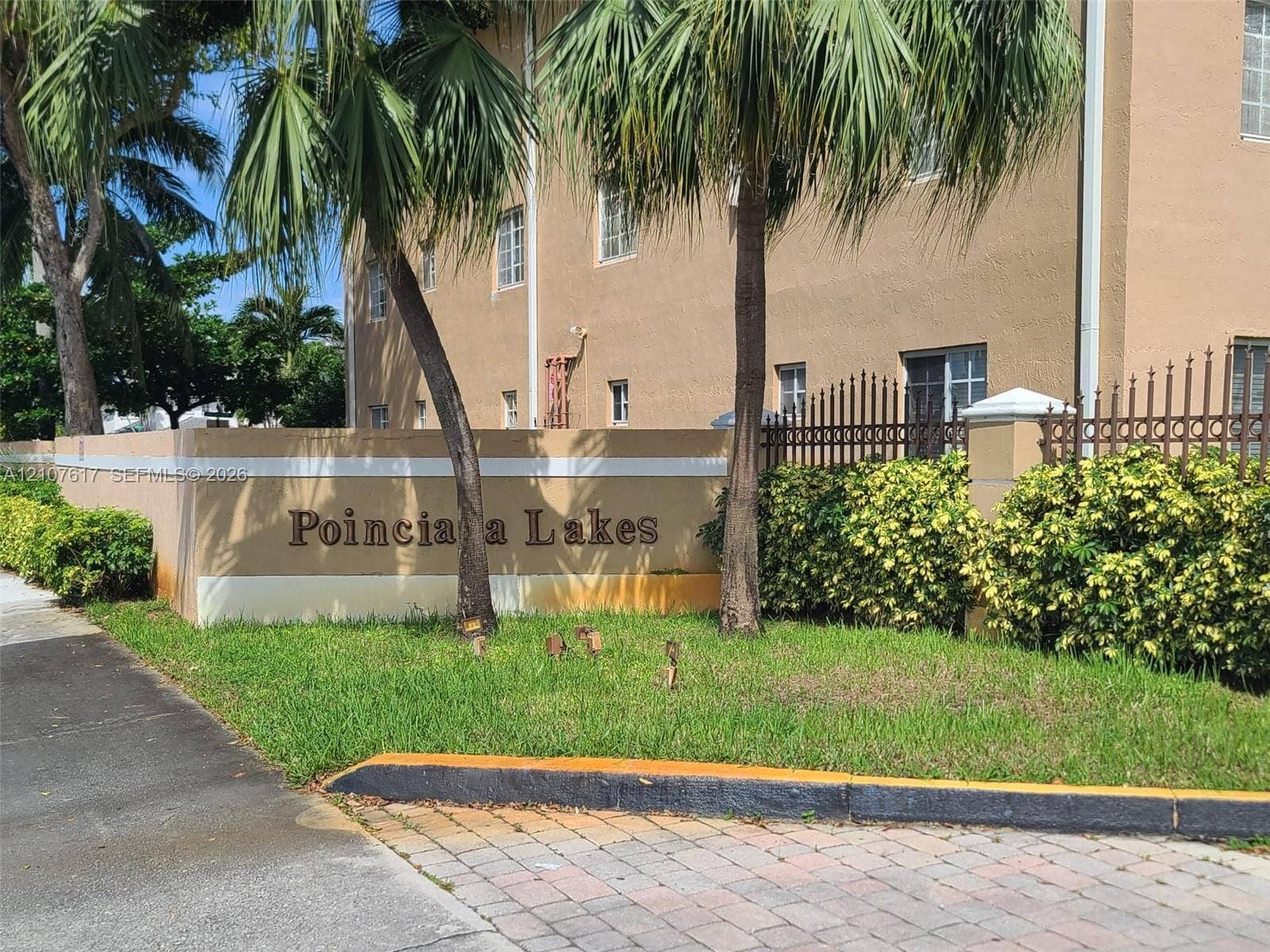 17415 NW 75th Place, #103, Hialeah, Hialeah, FL 33015 Stucco monument signage featuring ornamental metal fencing, concrete paver drive entry, and mature palm landscaping