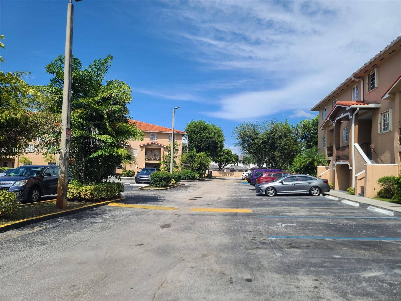 17415 NW 75th Place, #103, Hialeah, Hialeah, FL 33015 Asphalt-paved surface parking area featuring designated spots and mature landscaping