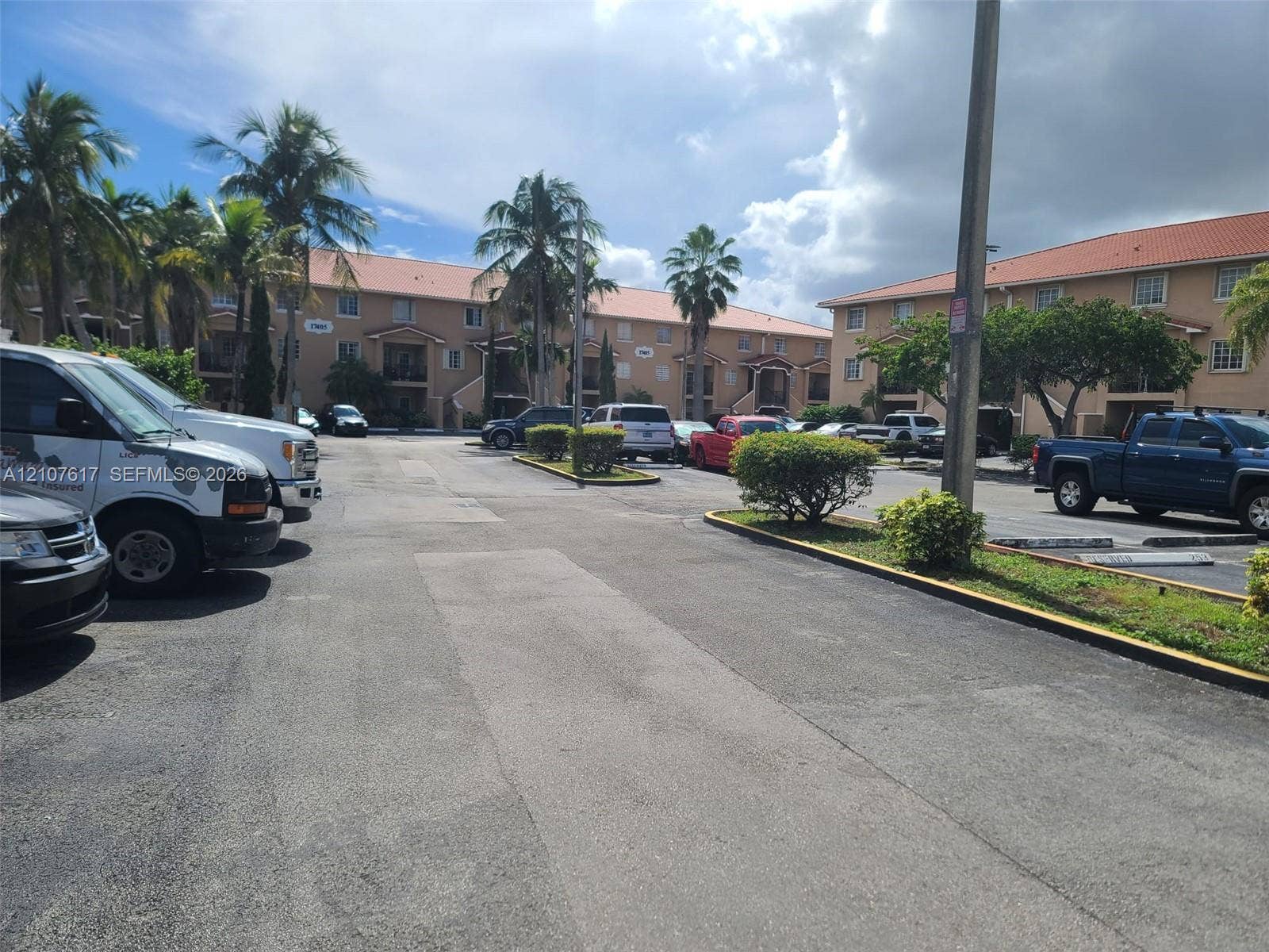17415 NW 75th Place, #103, Hialeah, Hialeah, FL 33015 Multi-story stucco exterior featuring clay tile roofing, concrete paved parking areas, and established palm trees