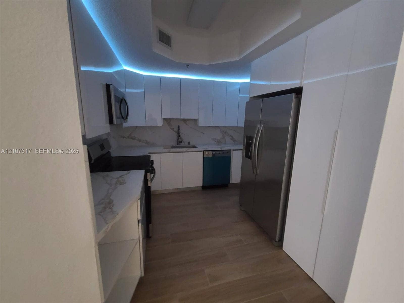 17415 NW 75th Place, #103, Hialeah, Hialeah, FL 33015 Kitchen featuring high-gloss white cabinetry, stone-patterned countertops, integrated lighting, stainless steel appliances, and wood-finish flooring