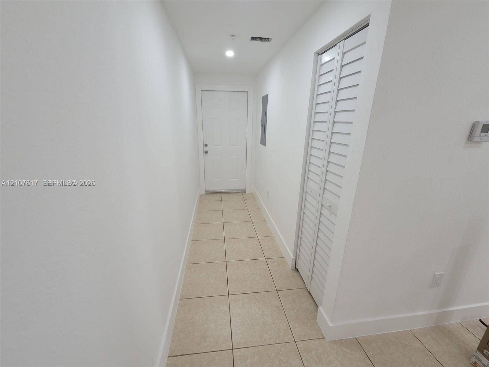 17415 NW 75th Place, #103, Hialeah, Hialeah, FL 33015 Interior hallway featuring neutral ceramic tile flooring, a six-panel door, and closet doors with louvered panels