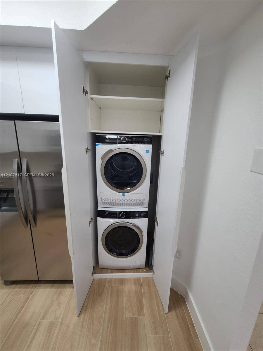 17415 NW 75th Place, #103, Hialeah, Hialeah, FL 33015 Built-in laundry closet with stacked washer and dryer, integrated shelving, and wood-finish flooring