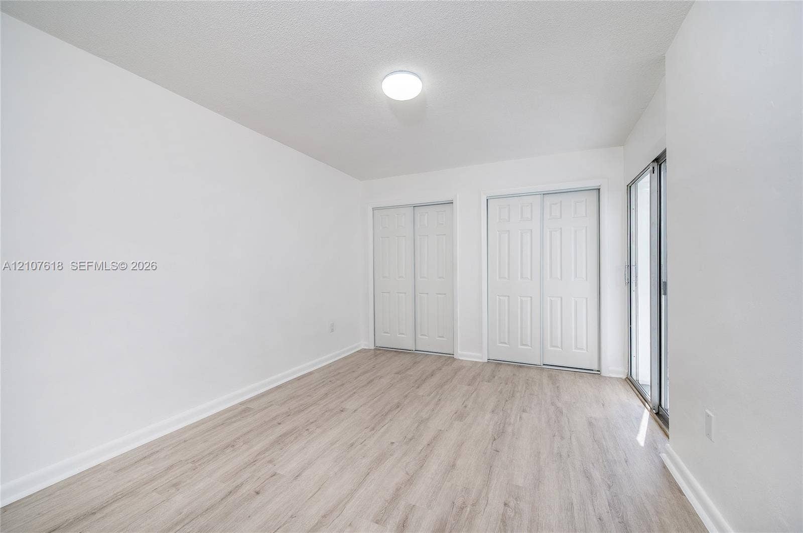 444 SW 27th Avenue, #46, Miami, Miami, FL 33135 Neutral-toned wood-finish flooring, two sets of white paneled closet doors, and a sliding glass door