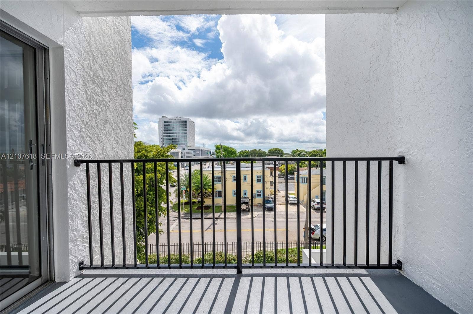 444 SW 27th Avenue, #46, Miami, Miami, FL 33135 Covered balcony with textured stucco walls, black metal railing, and sliding glass entry door