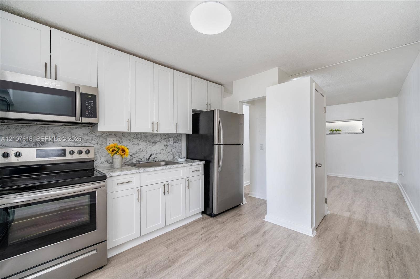 444 SW 27th Avenue, #46, Miami, Miami, FL 33135 Kitchen featuring white shaker-style cabinetry, stone-finish countertops, full-height decorative backsplash, stainless steel appliances, and wood-finish flooring