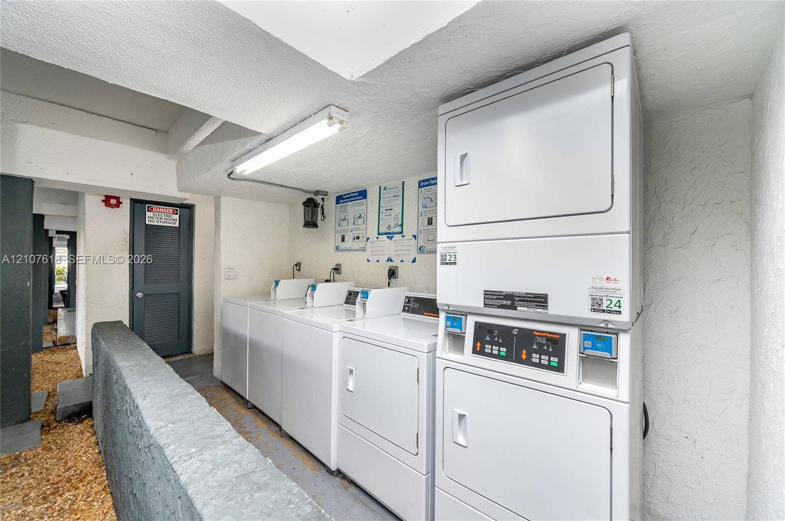 444 SW 27th Avenue, #46, Miami, Miami, FL 33135 Shared laundry area featuring stacked and side-by-side white washer and dryer units, fluorescent overhead lighting, and textured wall finishes