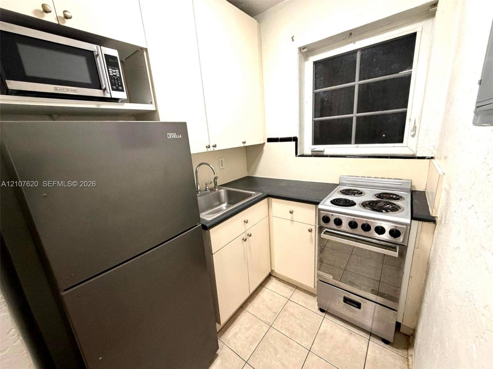 260 Euclid Avenue, #29, Miami Beach, Miami Beach, FL 33139 Kitchen featuring white flat-panel cabinetry, dark countertops, a stainless steel sink with a curved faucet, a stainless steel range, and tile flooring