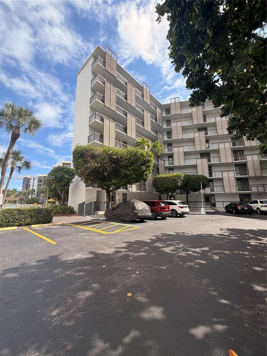 20400 W Country Club Drive, #112, Aventura, FL 33180 Mid-rise exterior featuring vertical architectural privacy screens, private balconies, and asphalt surface parking