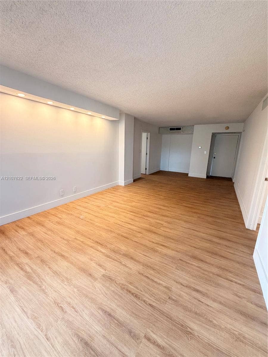 20400 W Country Club Drive, #112, Aventura, FL 33180 Open floor plan featuring wood-finish flooring, recessed soffit lighting, and neutral wall tones