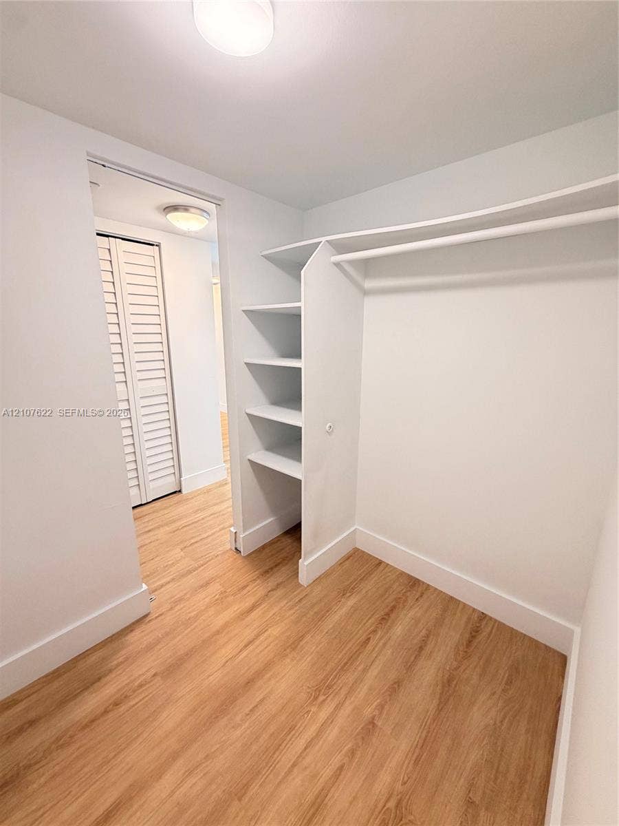 20400 W Country Club Drive, #112, Aventura, FL 33180 Walk-in closet featuring wood-finish flooring, built-in shelving, and a hanging rod