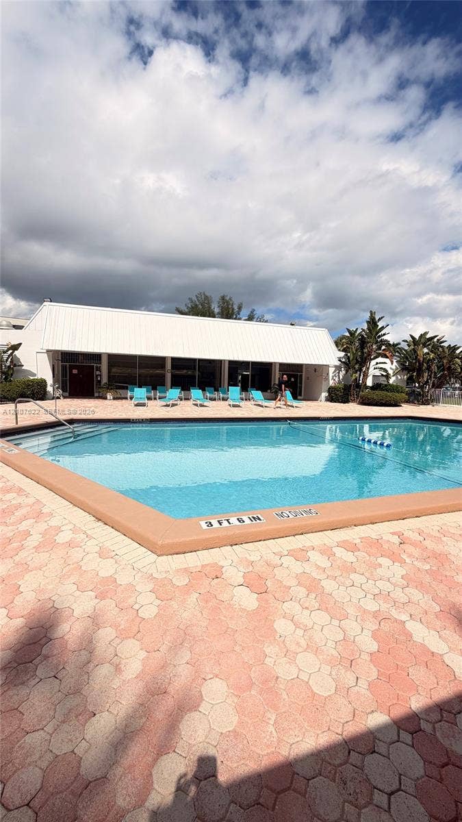 20400 W Country Club Drive, #112, Aventura, FL 33180 In-ground swimming pool featuring a paved perimeter, metal railings, and a wide-brimmed pavilion roof