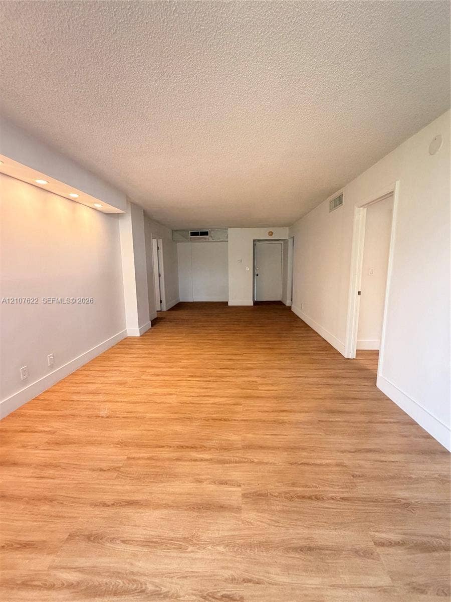 20400 W Country Club Drive, #112, Aventura, FL 33180 Open-concept interior featuring wood-finish flooring, recessed architectural soffit lighting, and neutral wall tones