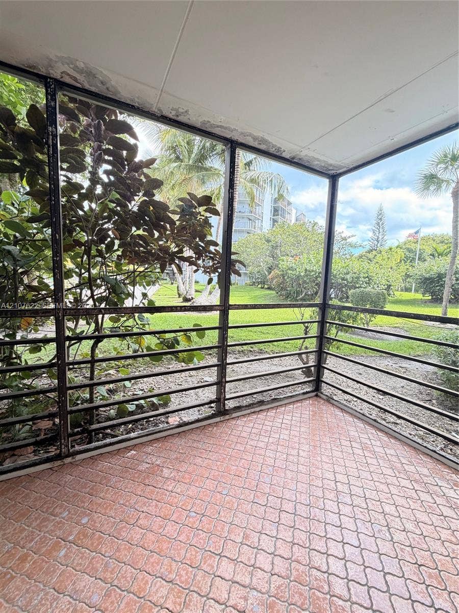 20400 W Country Club Drive, #112, Aventura, FL 33180 Enclosed screened patio featuring terra cotta tile flooring and dark metal framing