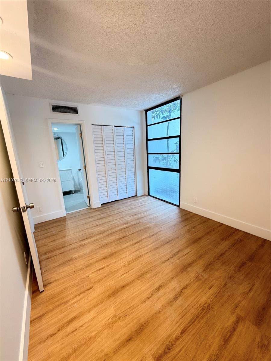 20400 W Country Club Drive, #112, Aventura, FL 33180 Wood-finish flooring, floor-to-ceiling multi-panel fixed window, and white louvered-style closet doors