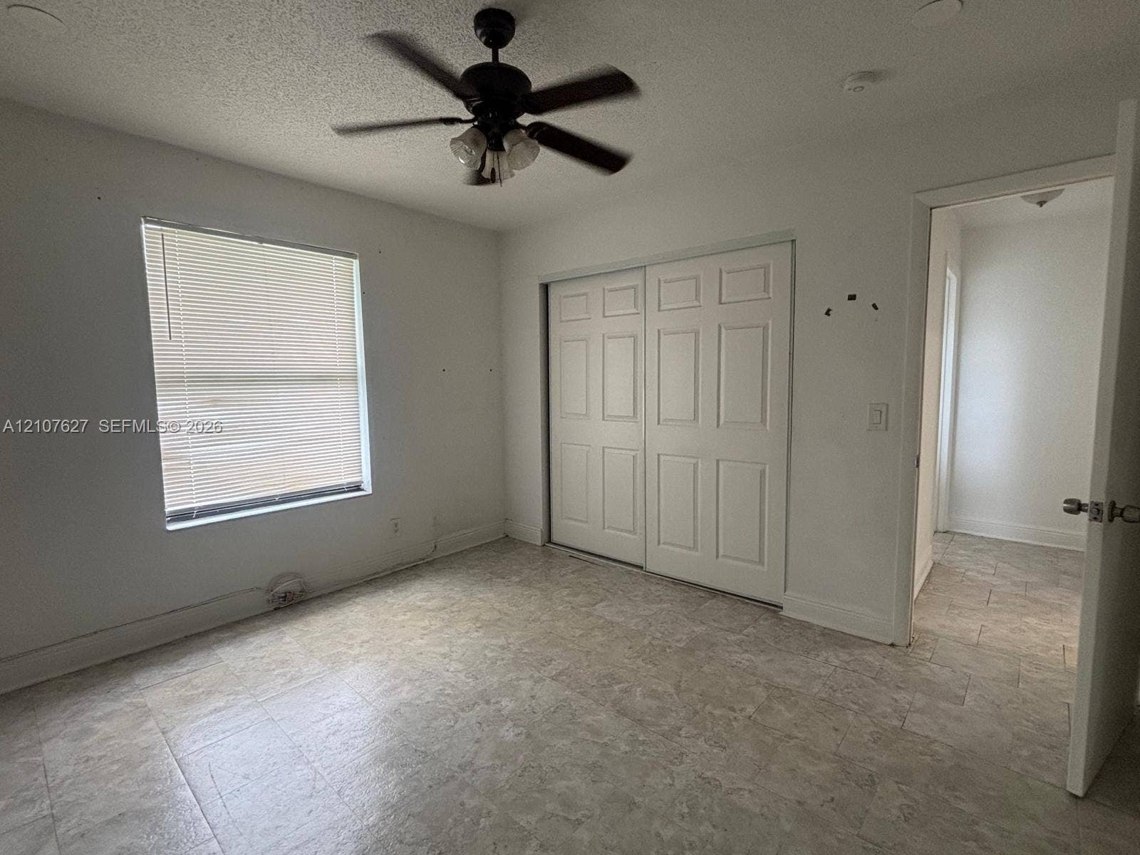 19 Crossings Circle, #H, Boynton Beach, Boynton Beach, FL 33435 Neutral interior room featuring neutral-toned tile flooring, white walls, a multi-panel sliding closet, and a ceiling fan with integrated lighting