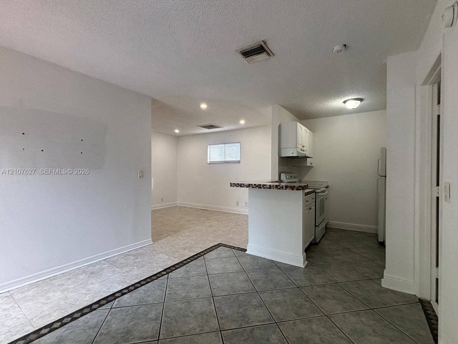 19 Crossings Circle, #H, Boynton Beach, Boynton Beach, FL 33435 Kitchen featuring a breakfast bar, white cabinetry, and tile flooring