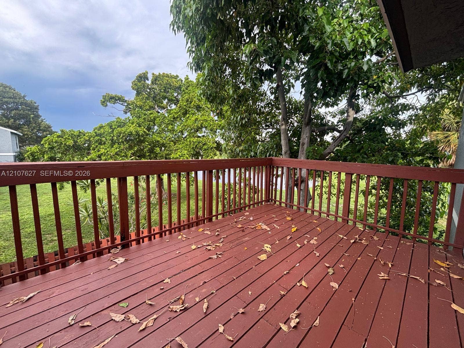 19 Crossings Circle, #H, Boynton Beach, Boynton Beach, FL 33435 Elevated deck featuring wood-finish decking, horizontal railings, and mature trees