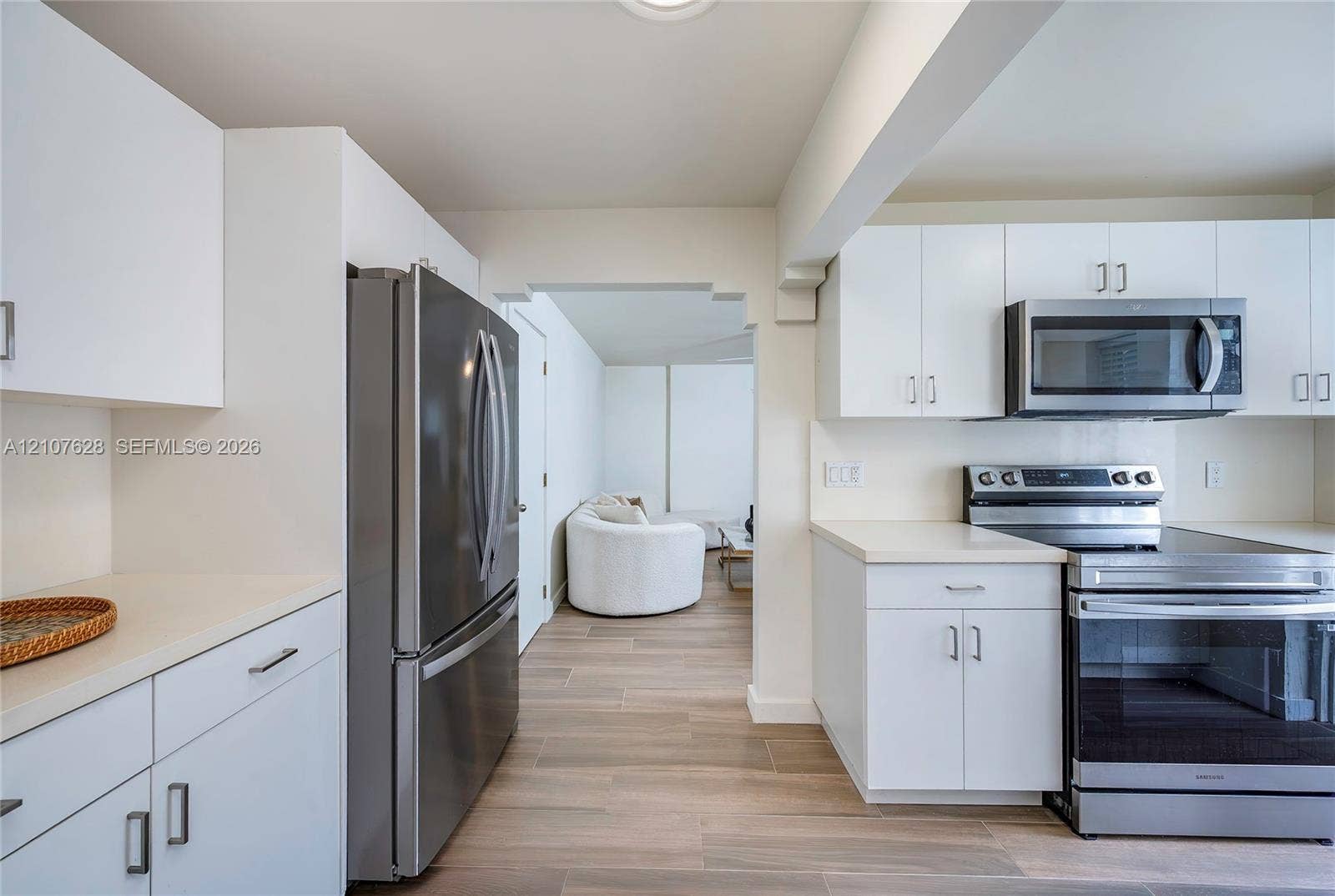 217 Madeira Avenue, #1, Coral Gables, Coral Gables, FL 33134 Kitchen featuring white cabinetry, stainless steel appliances, wood-finish flooring, and solid-surface countertops