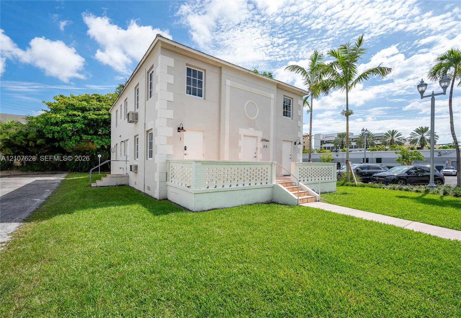 217 Madeira Avenue, #1, Coral Gables, Coral Gables, FL 33134 Two-story building featuring a smooth stucco exterior, decorative stone-finish corner quoins, a raised terrace with a lattice-style masonry railing, and tiled stairs