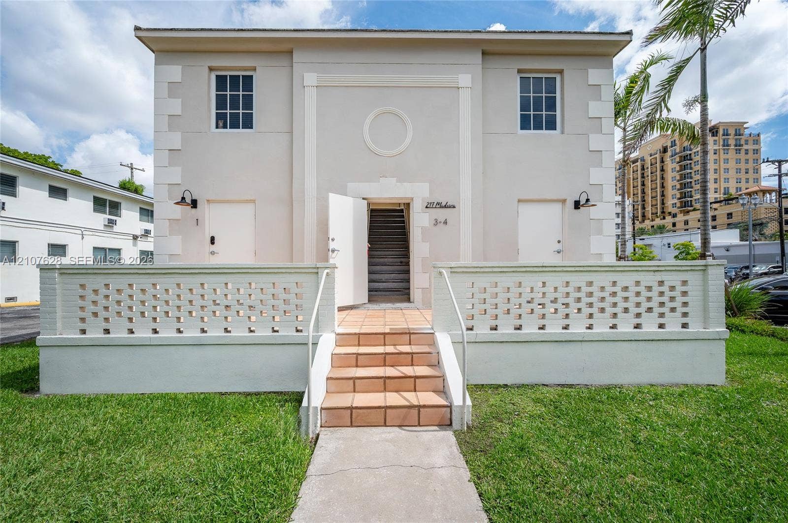 217 Madeira Avenue, #1, Coral Gables, Coral Gables, FL 33134 Stucco exterior featuring quoined corner details, decorative medallion molding, a low-profile masonry privacy wall, and terracotta-tiled entrance steps