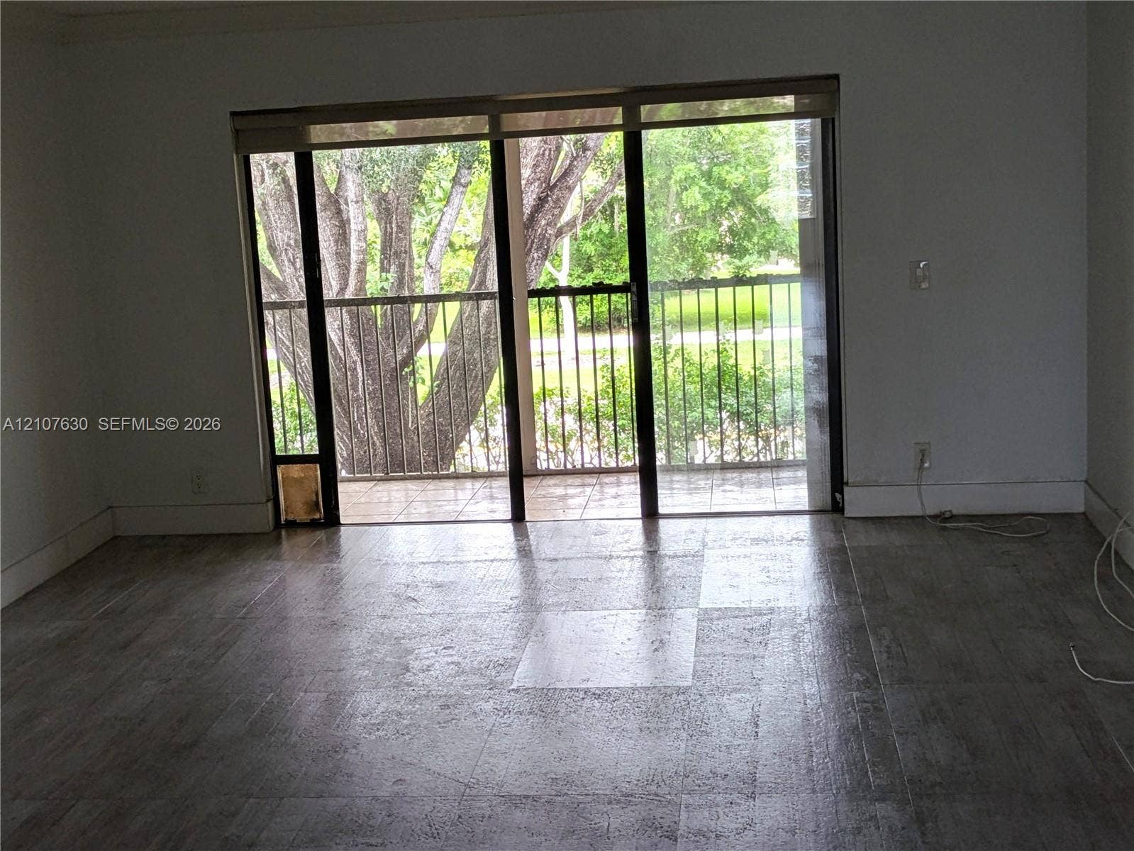 Floor-to-ceiling sliding glass door with integrated blinds, providing access to a covered exterior balcony featuring a metal railing