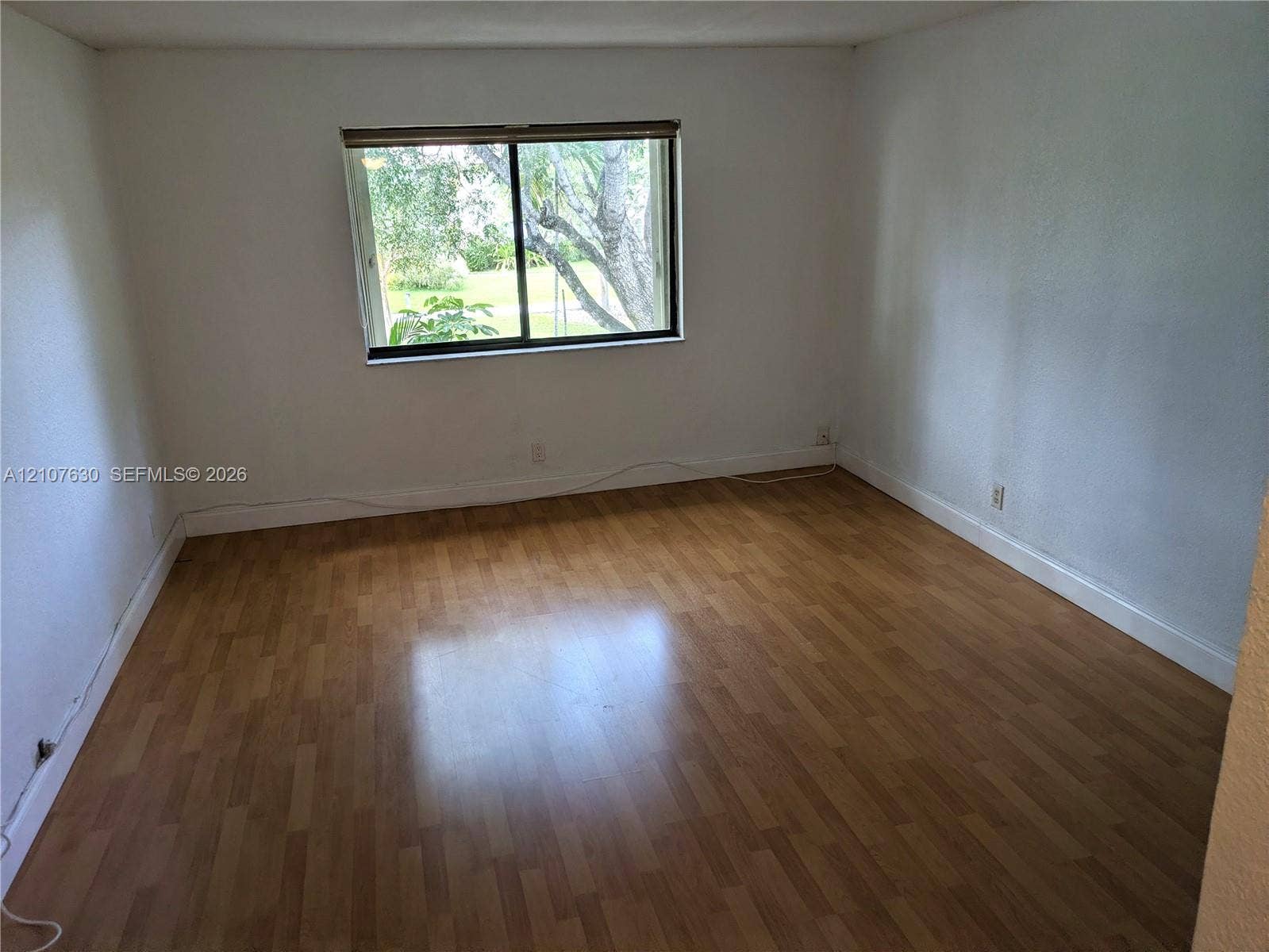 Room featuring wood-finish flooring, white walls, and a horizontal sliding window