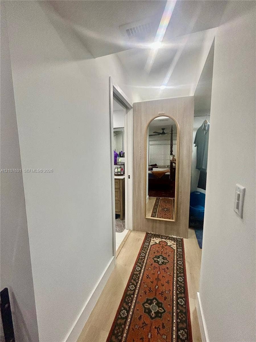 151 Berkley Road, #112, Hollywood, FL 33024 Hallway featuring wood-finish flooring and a built-in wood-panel wall section with a recessed arched mirror