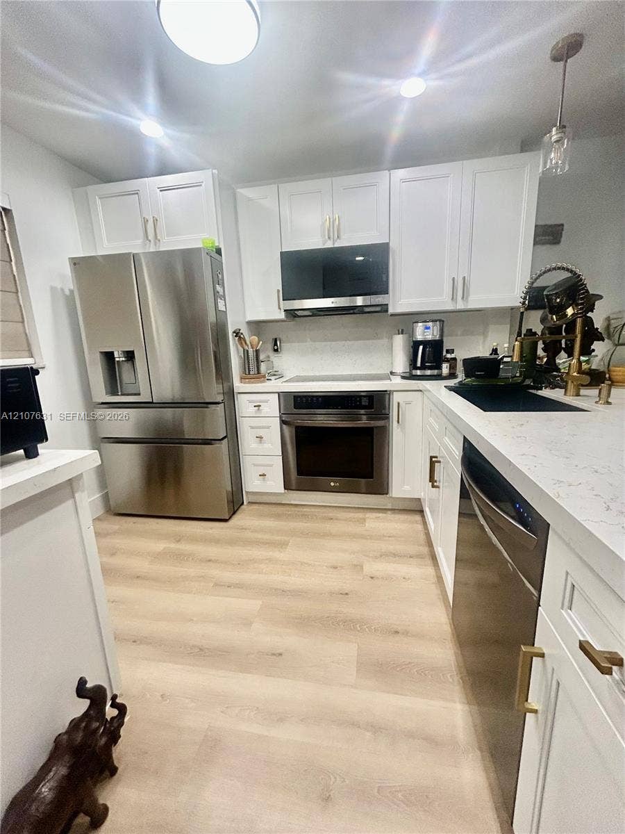 151 Berkley Road, #112, Hollywood, FL 33024 Kitchen featuring white cabinetry, quartz countertops, stainless steel appliances, and wood-finish flooring