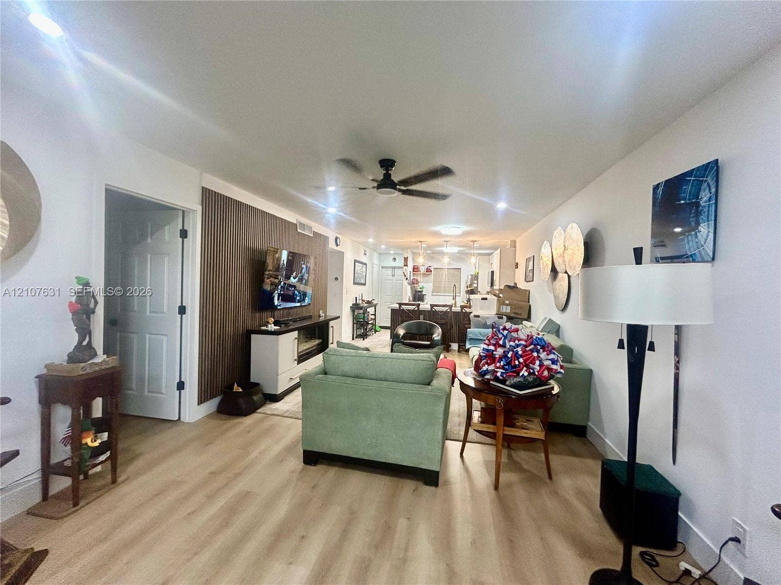 151 Berkley Road, #112, Hollywood, FL 33024 Open-concept living space featuring wood-finish flooring, vertical slat wood-tone accent wall, recessed lighting, and a ceiling fan