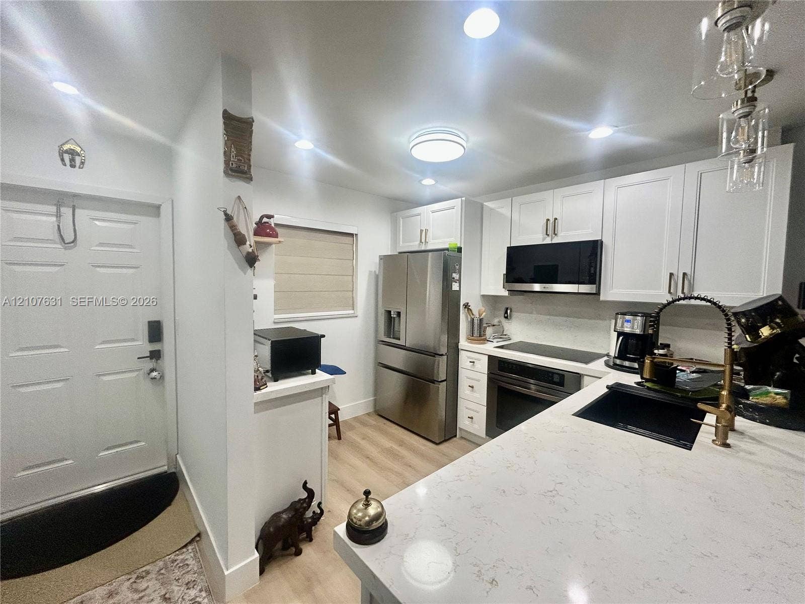 151 Berkley Road, #112, Hollywood, FL 33024 Kitchen featuring white cabinetry, quartz countertops, stainless steel appliances, wood-finish flooring, and a gooseneck faucet