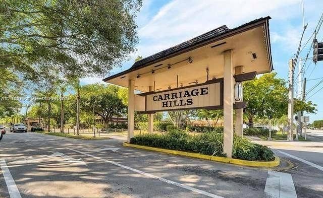 151 Berkley Road, #112, Hollywood, FL 33024 Monument signage featuring structured overhead roofing, mounted spotlights, and landscaping at the entrance