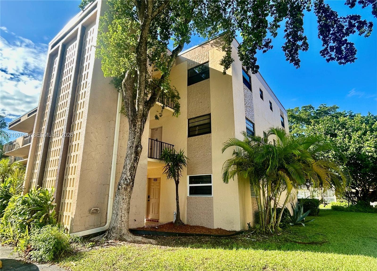 151 Berkley Road, #112, Hollywood, FL 33024 Multi-story stucco exterior featuring decorative concrete screen panels, private balconies with metal railings, and established landscaping