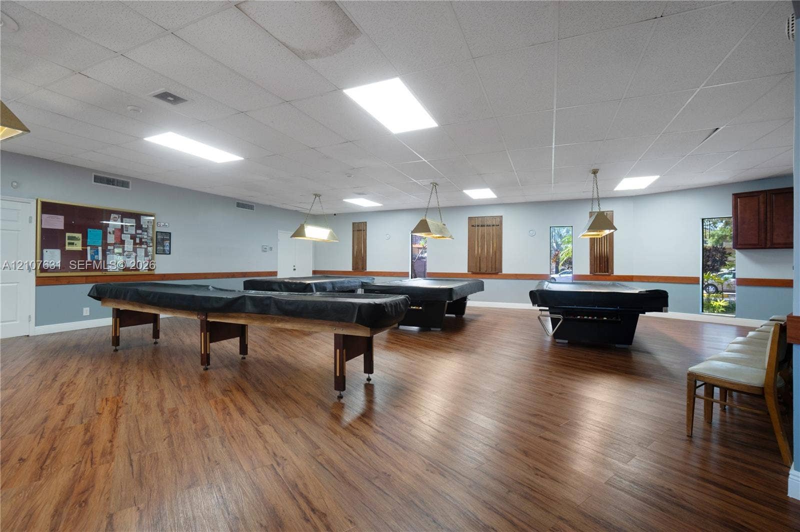 151 Berkley Road, #112, Hollywood, FL 33024 Expansive room featuring wood-finish flooring, drop ceiling with recessed lighting, suspended pendant lighting, wainscoting, and built-in wall cabinetry