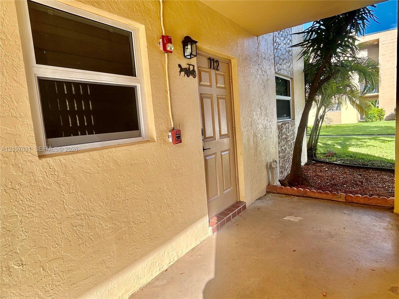 151 Berkley Road, #112, Hollywood, FL 33024 Covered entryway featuring textured stucco exterior, six-panel entry door, and stone-accented faade