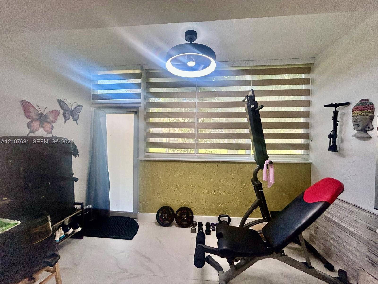 151 Berkley Road, #112, Hollywood, FL 33024 Room featuring large-format tile flooring, textured wall accents, a modern flush-mount LED circular light fixture, and horizontal dual-layer window treatments