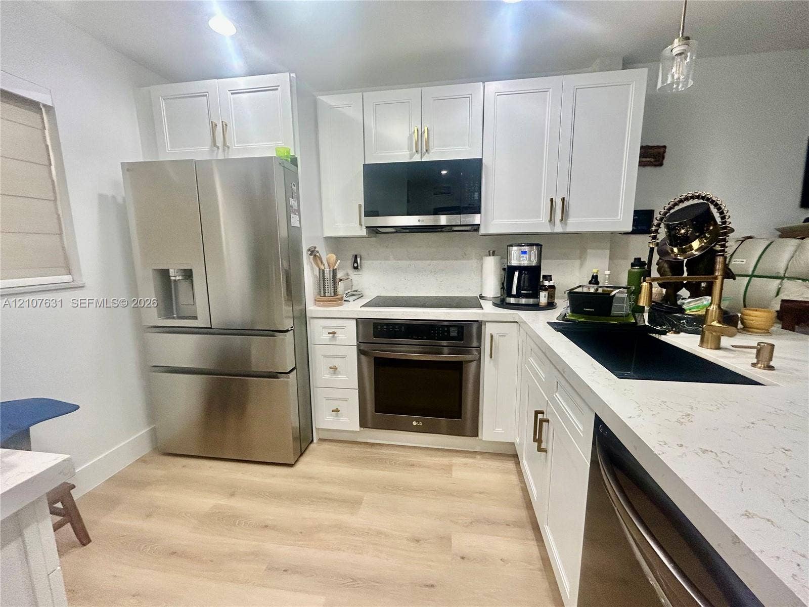151 Berkley Road, #112, Hollywood, FL 33024 Kitchen featuring white shaker-style cabinetry, quartz countertops, wood-finish flooring, and stainless steel appliances