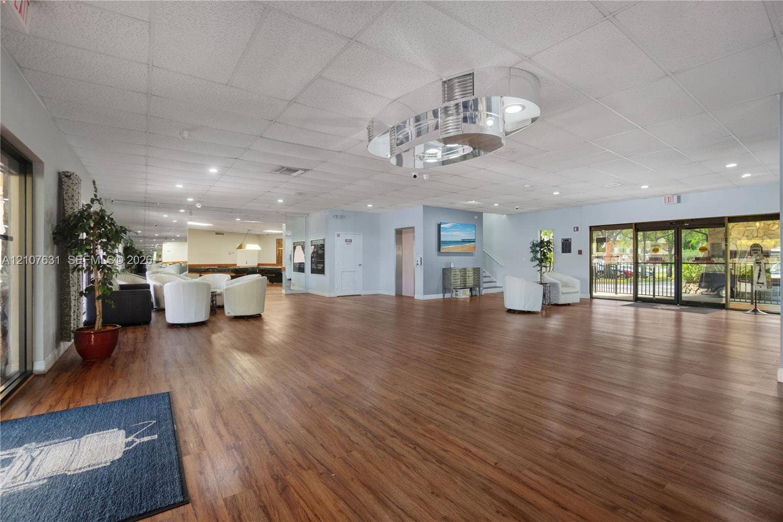 151 Berkley Road, #112, Hollywood, FL 33024 Open-concept interior featuring wood-finish flooring, recessed lighting, a modern polished-metal circular pendant fixture, and floor-to-ceiling glass sliding entry doors
