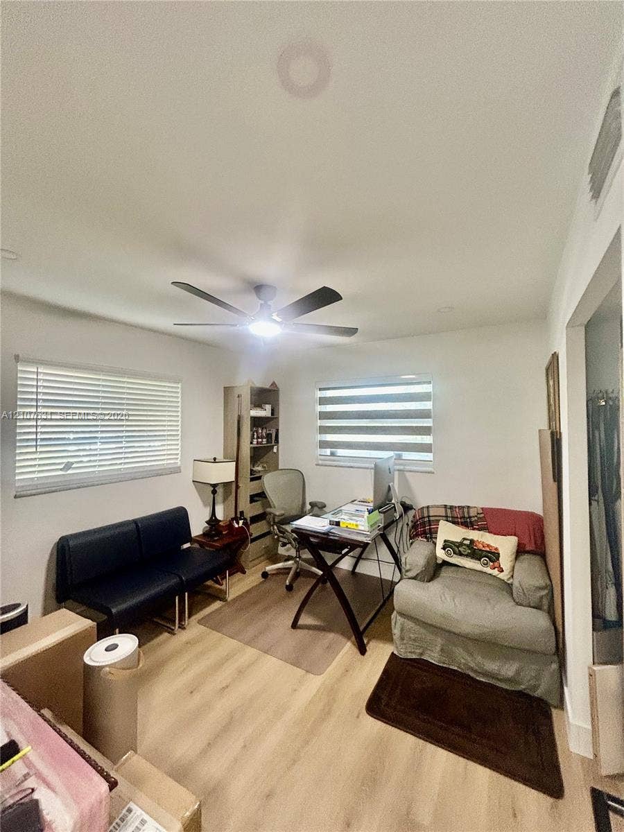 151 Berkley Road, #112, Hollywood, FL 33024 Room featuring neutral wall paint, wood-finish flooring, a ceiling fan with integrated lighting, and dual windows with horizontal blinds