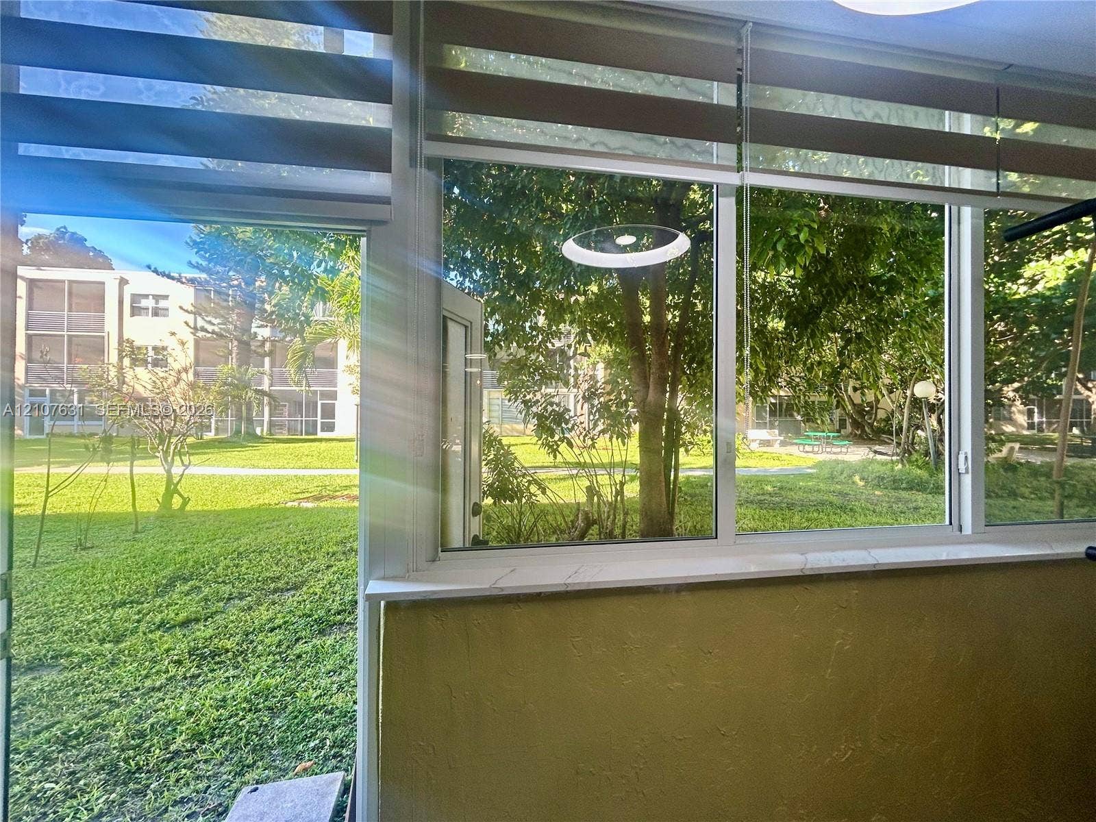 151 Berkley Road, #112, Hollywood, FL 33024 Floor-to-ceiling windows featuring adjustable dual-layer fabric shades, a white stone-finish sill, and an integrated circular light fixture
