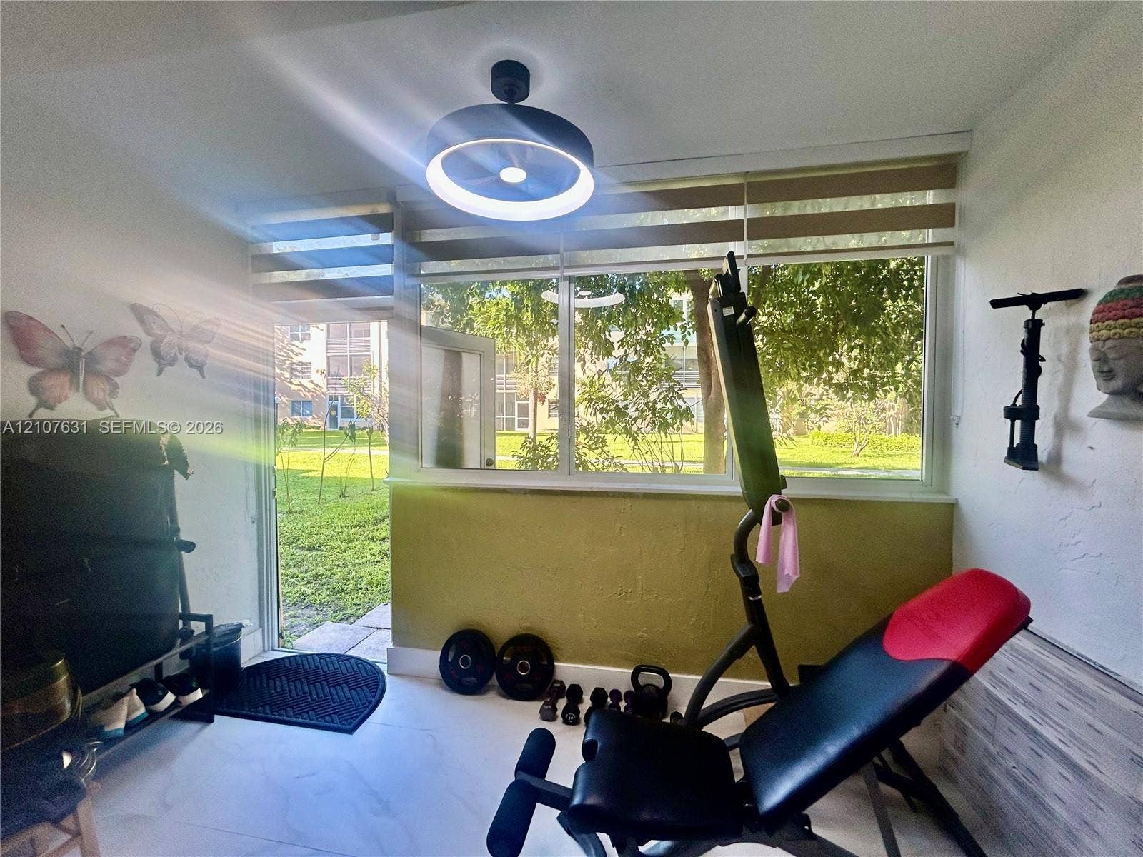 151 Berkley Road, #112, Hollywood, FL 33024 Large window with horizontal blinds, modern circular LED ceiling fixture, neutral tile flooring, and exterior access door